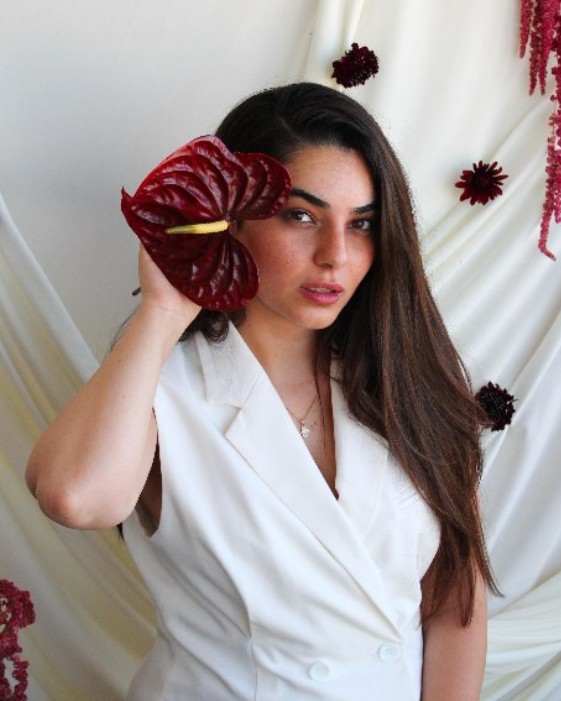 Paz, founder of Floro Design, holding a dark red anthurium bloom